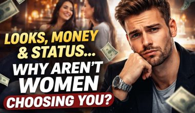 A man with a puzzled expression sits in the foreground, surrounded by floating dollar bills. In the background, two women converse in a warmly lit bar. Text reads, "Looks, money & status... Why aren’t women choosing you?" The scene suggests themes of dating and self-reflection.